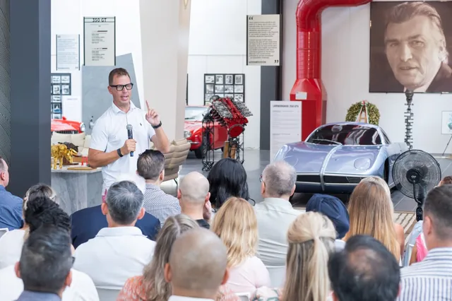 JT Foxx speaking to an audience among Lamborghini cars and exhibits