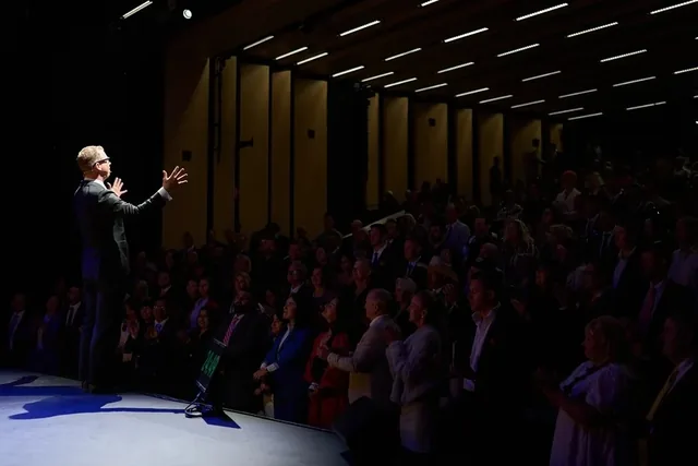 JT Foxx addressing an audience from a spotlighted stage