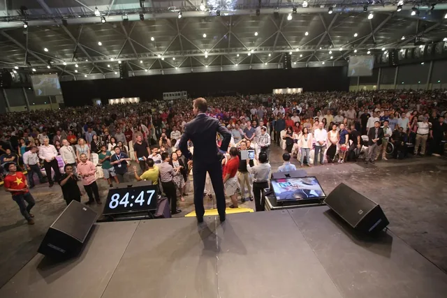 JT Foxx facing a full event audience with an 84:47 timer beside him